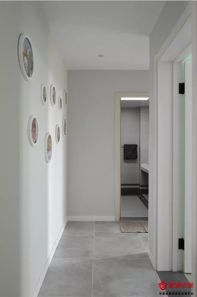 走廊灰色地面砖 浅灰色墙面,侧边的墙面挂着一组圆形装饰画,显得